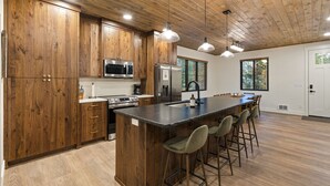 Una cocina moderna con armarios de madera, electrodomésticos de acero inoxidable y una isla central con taburetes de bar.