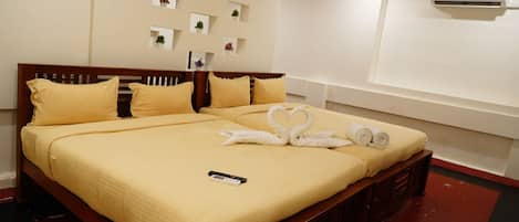 Una cama bien tendida con un control remoto encima, un aire acondicionado de pared y varios pequeños maceteros en la pared.