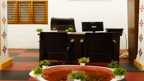 A reception area with a desk, two chairs, a framed picture on the wall, and a decorative water feature in the foreground. - White Town Villa  (Puducherry)