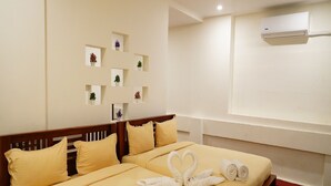 A hotel room with a bed, pillows, a remote control, and a wall-mounted air conditioner. - White Town Villa  (Puducherry)