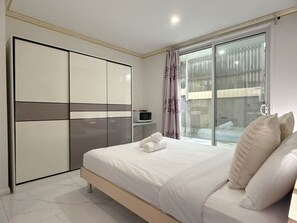 A bedroom with a bed, a wardrobe, a television, and a window with curtains.