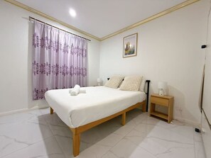 A bedroom with a bed, a nightstand, a lamp, a window with curtains, and a picture on the wall. - Malls at Doorstep:2-Bed Unit in Heart ofCannonHill (Cannon Hill)
