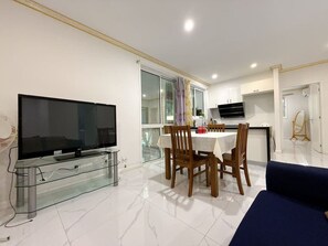 A modern living room with a flat-screen TV, a glass coffee table, and a blue sofa. - Malls at Doorstep:2-Bed Unit in Heart ofCannonHill (Cannon Hill)