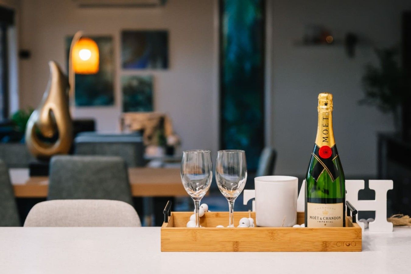 A bottle of Moët & Chandon champagne, two glasses, and a tray with a white cup on a table.