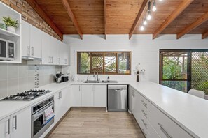 A modern kitchen with white cabinetry, a stainless steel dishwasher, and a gas stove.