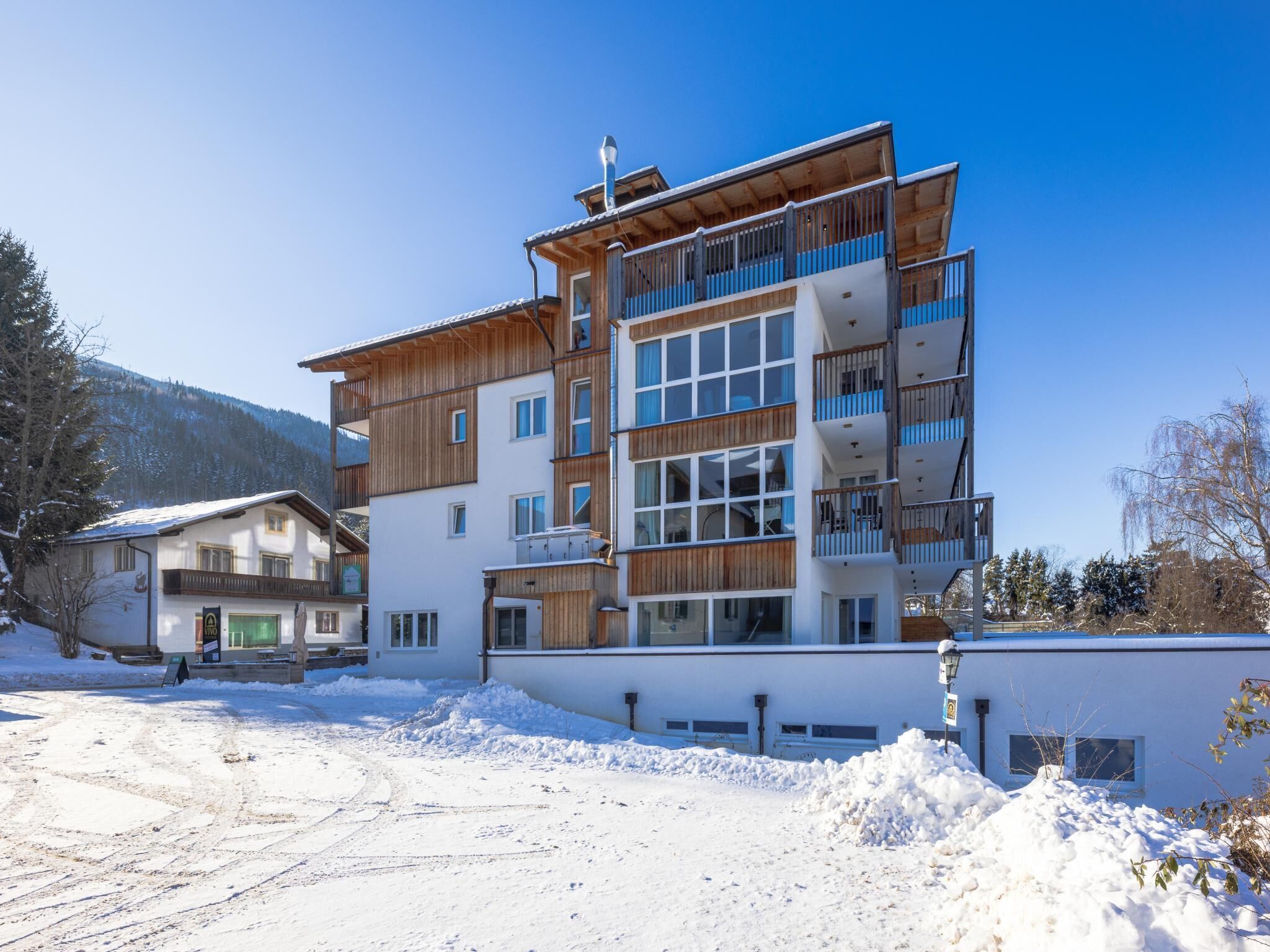 Un hotel de diverses plantes amb balcons, un remuntador d'esquí i un paisatge nevós.