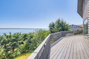 En træterrasse med gelænder, udsigt over vand og frodig vegetation.