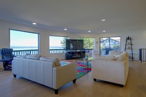 Un salon spacieux avec une grande fenêtre, un téléviseur et un balcon.