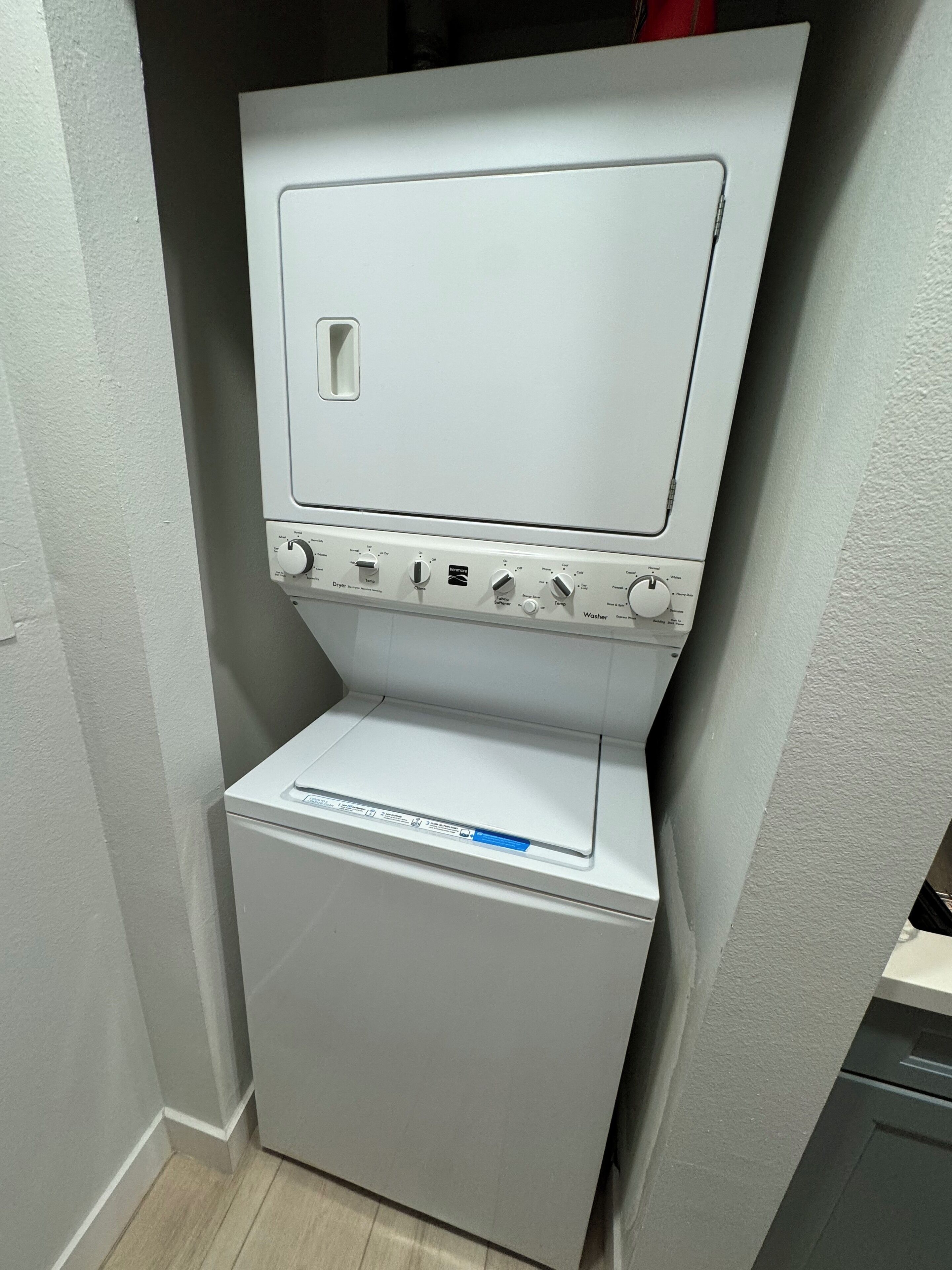 A compact, white, wall-mounted washer and dryer unit with a control panel featuring multiple settings.