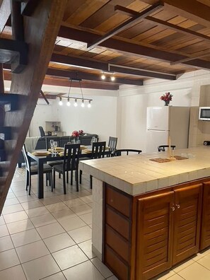 A modern kitchen with a large island, wooden cabinets, and a dining area with a table and chairs.