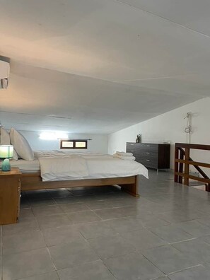 Un dormitorio con cama, mesita de noche, cómoda y barandilla de madera.