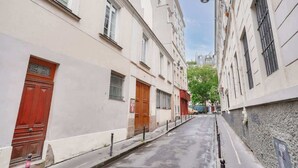 Une rue étroite bordée d’immeubles, où se côtoient des bâtiments résidentiels et des locaux commerciaux.