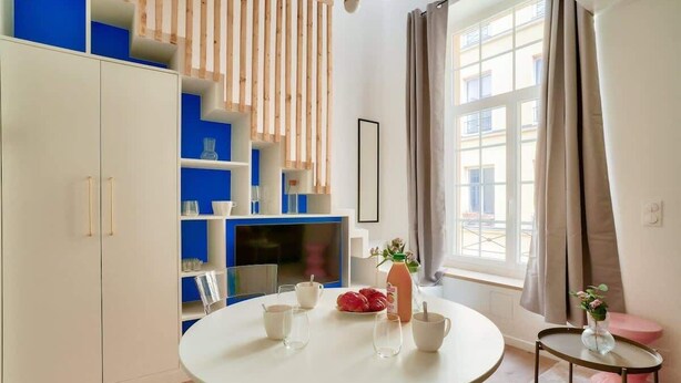 Une cuisine moderne avec des meubles blancs, une table de salle à manger ronde et un téléviseur.