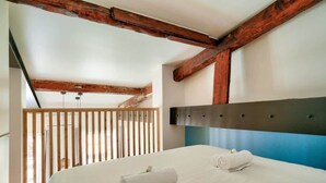 A bedroom with a bed, wooden beams, a balcony, and a modern headboard. - Perchoir Parisien - Dupleix avec mezzanine pour 4 (Paris)