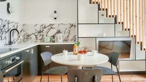 A modern kitchen with a marble backsplash, stainless steel appliances, and a round dining table with four chairs. - Perchoir Parisien - Dupleix avec mezzanine pour 4 (Paris)