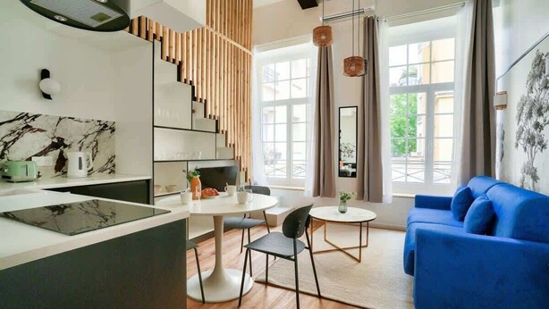 A modern living space with a kitchen, dining area, and a blue sofa. - Perchoir Parisien - Dupleix avec mezzanine pour 4 (Paris)