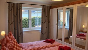 Quarto com duas camas, um espelho grande e uma janela com cortinas.