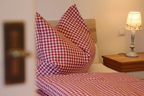 Un lit avec une literie à carreaux, une lampe de chevet et une table de chevet en bois.