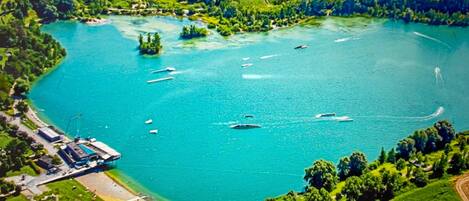 An aerial view of a lake surrounded by greenery, boats, and a dock area.