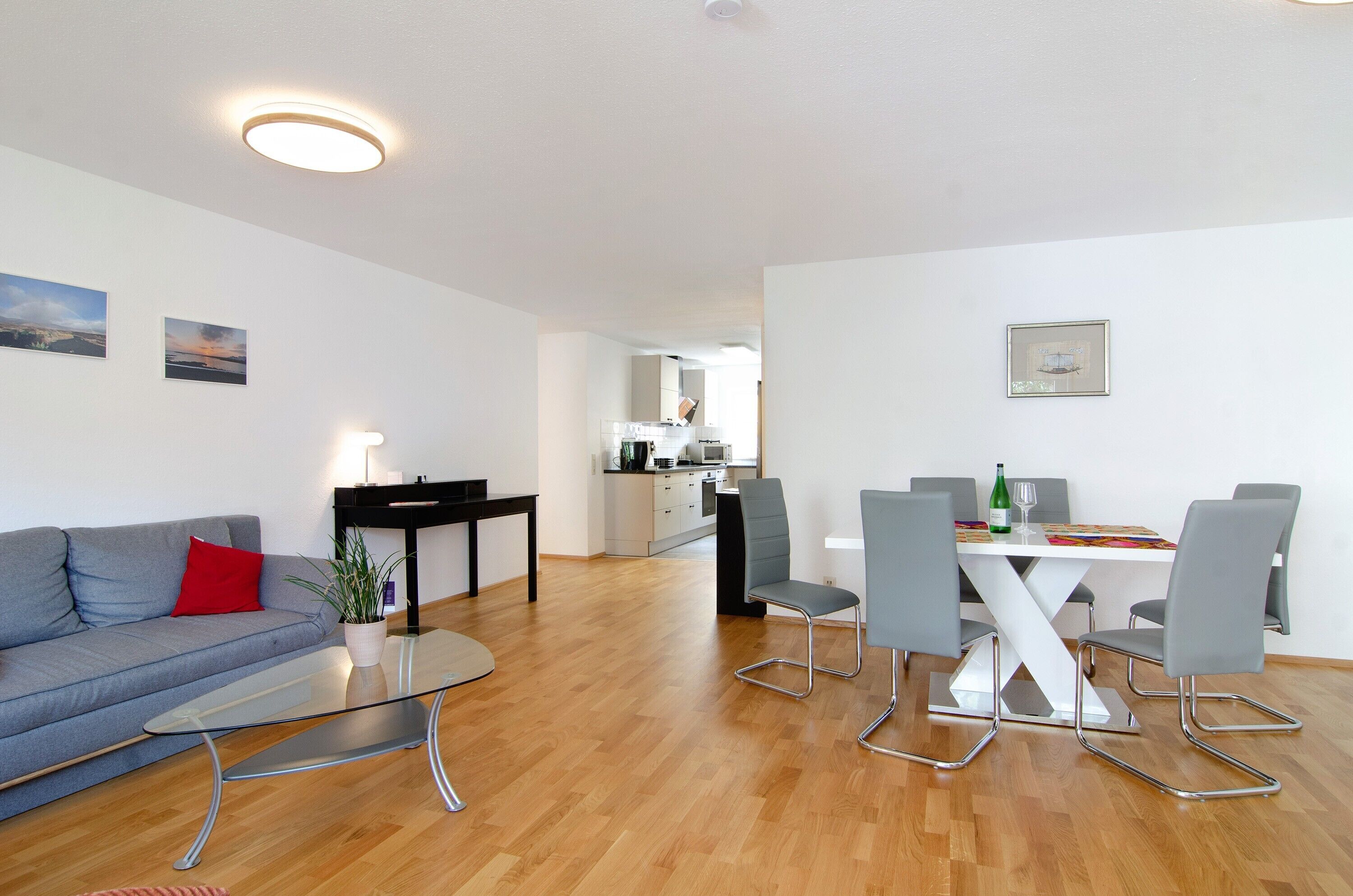 Una sala de estar moderna con un sofá, una mesa de centro de vidrio y un comedor con una mesa y sillas.