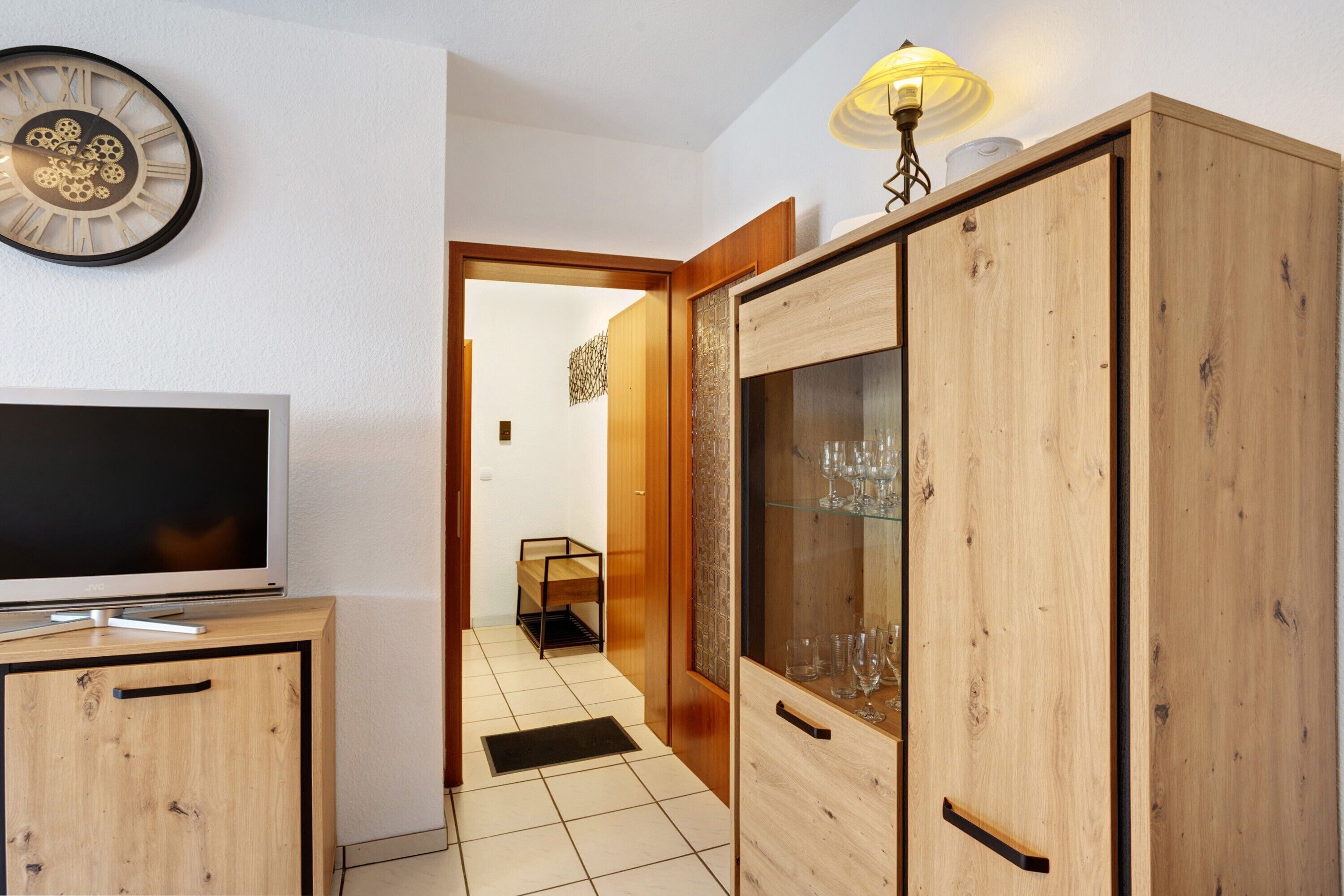 A hallway with wooden cabinets, a television, and a clock on the wall.