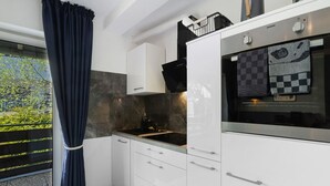A modern kitchen with white cabinets, a black countertop, and a window with a view of greenery.