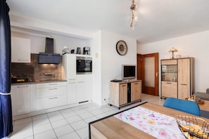 A compact kitchen with white cabinets, a built-in oven, and a coffee maker.