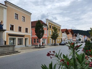 A street lined with colorful buildings, a statue, and a bench.