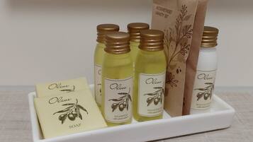 A set of olive-based personal care products including shampoo, shower gel, soap, and lotion, arranged on a white tray.