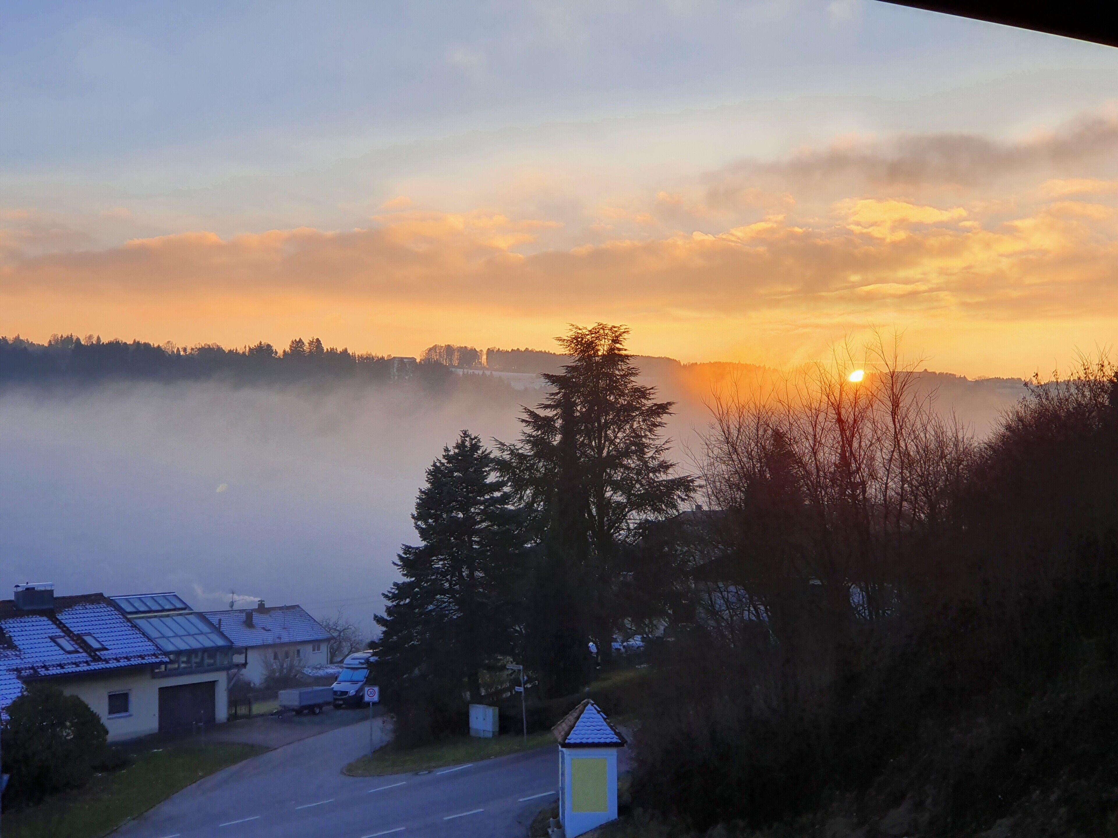 Ein Wohngebiet mit Häusern, einer Straße und einem kleinen Gebäude mit blauem Dach.