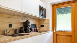 Une cuisine moderne dotée d’un plan de travail en bois, d’un évier en acier inoxydable et d’un four à micro-ondes encastré.