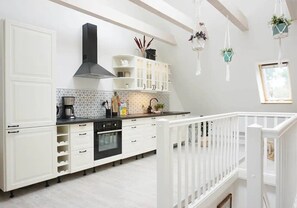 A modern kitchen with white cabinetry, a black range hood, and a white railing overlooking a balcony. - Apartment 'Gode Stuv' with Private Terrace, Shared Garden and Wi-Fi (Högel)
