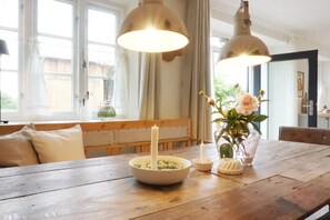 Una mesa de madera con un cuenco de aceitunas, una vela y un florero con flores.