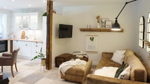 A living room with a sofa, ottoman, and a television mounted on the wall. - Apartment 'Lütje Orange' with Private Terrace, Shared Garden and Wi-Fi (Högel)