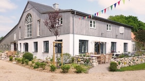 A two-story building with a large window and a stone wall. - Apartment 'Lütje Orange' with Private Terrace, Shared Garden and Wi-Fi (Högel)