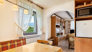A cozy kitchen with wooden cabinets, a dining table, and a view through an archway.