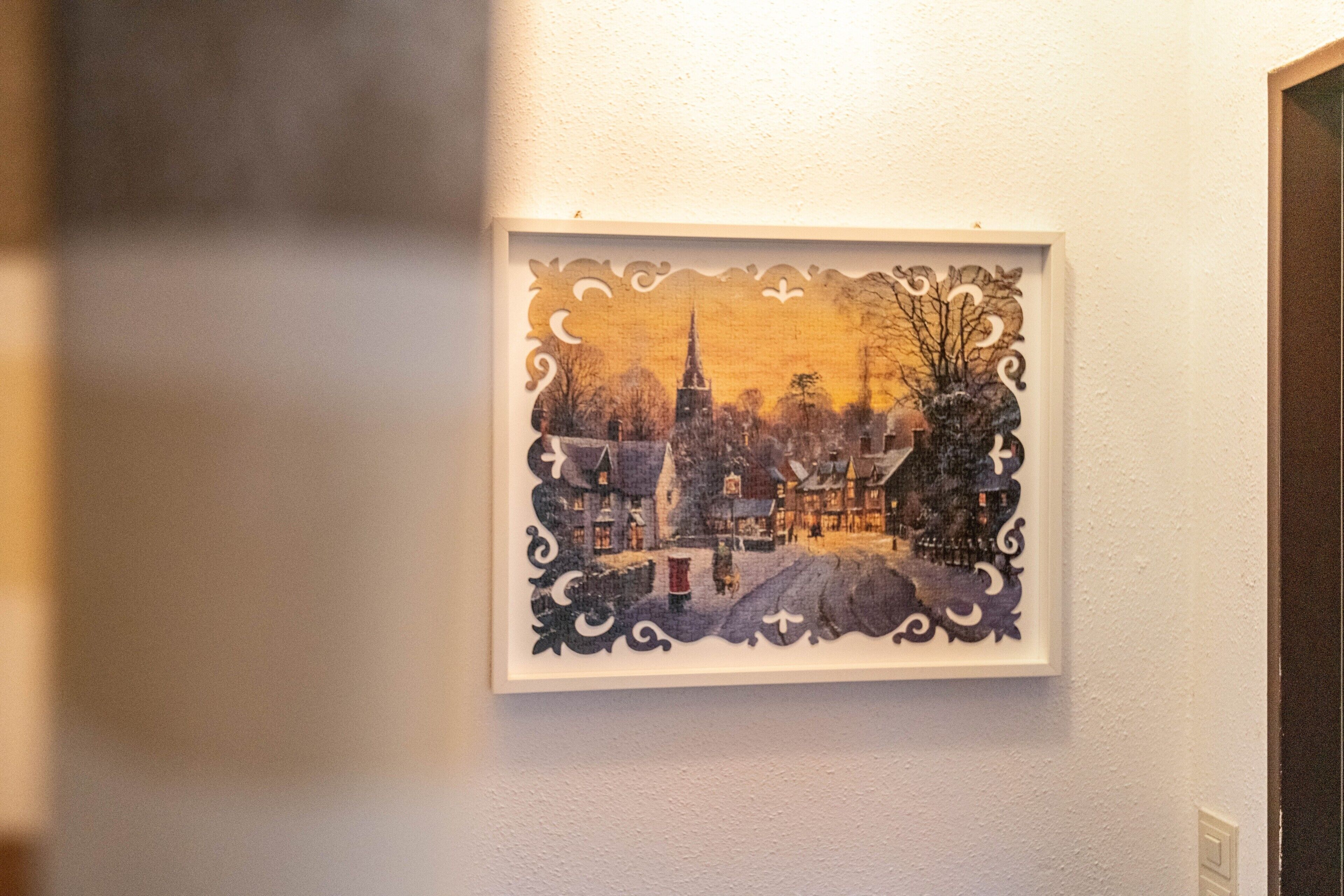 Ein gerahmtes Kunstwerk mit einer Stadtansicht an einer Wand.