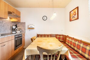 Una cocina con armarios de madera, una estufa y un comedor con mesa y bancos.
