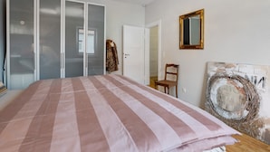 Un dormitori amb un llit, armari, cadira i una paret amb una obra d'art circular.