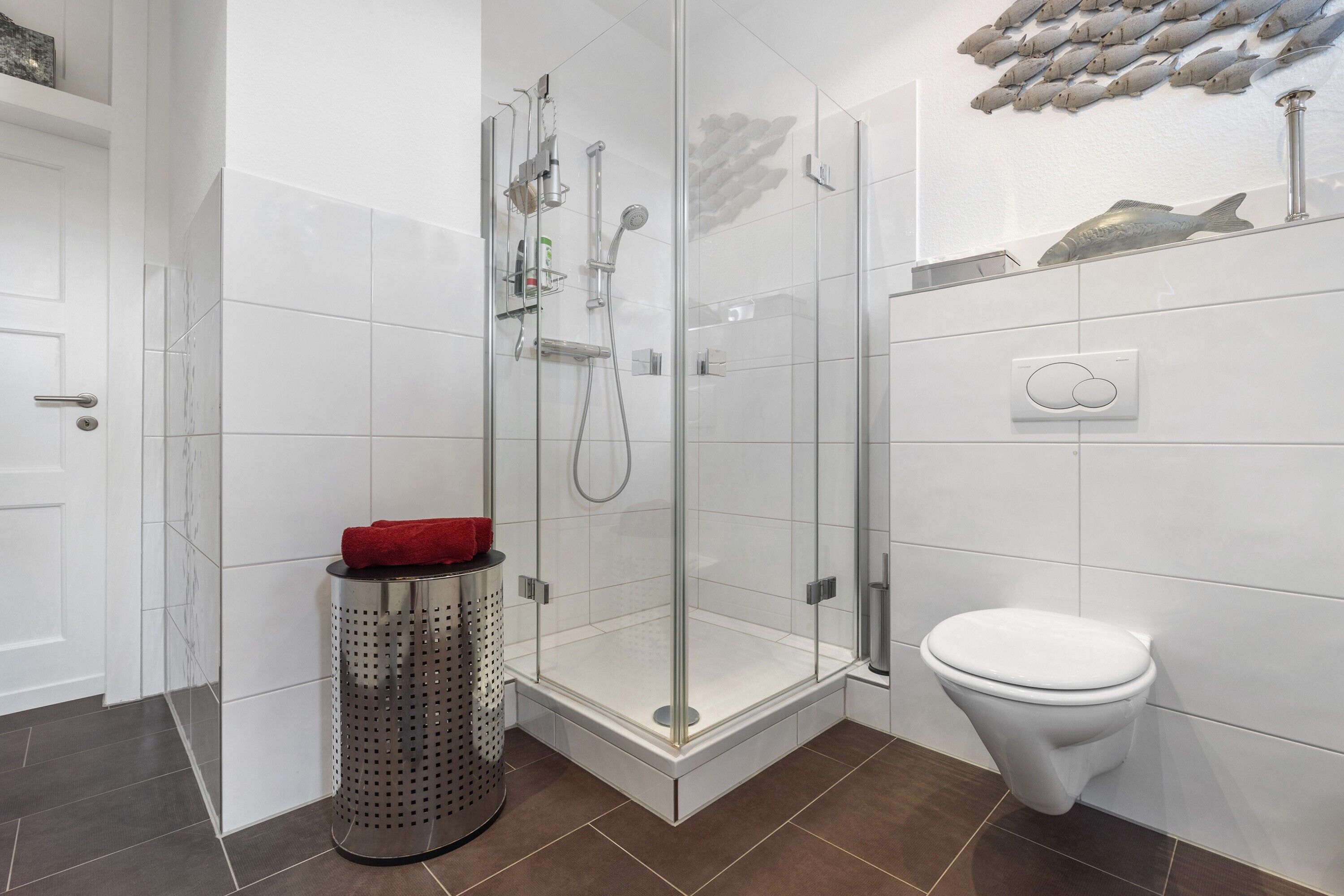 A modern bathroom with a glass-enclosed shower, a white toilet, and a tiled floor.