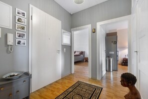 Ein Flur mit Holzboden, einem grauen Schminktisch und einem an der Wand befestigten Telefon.