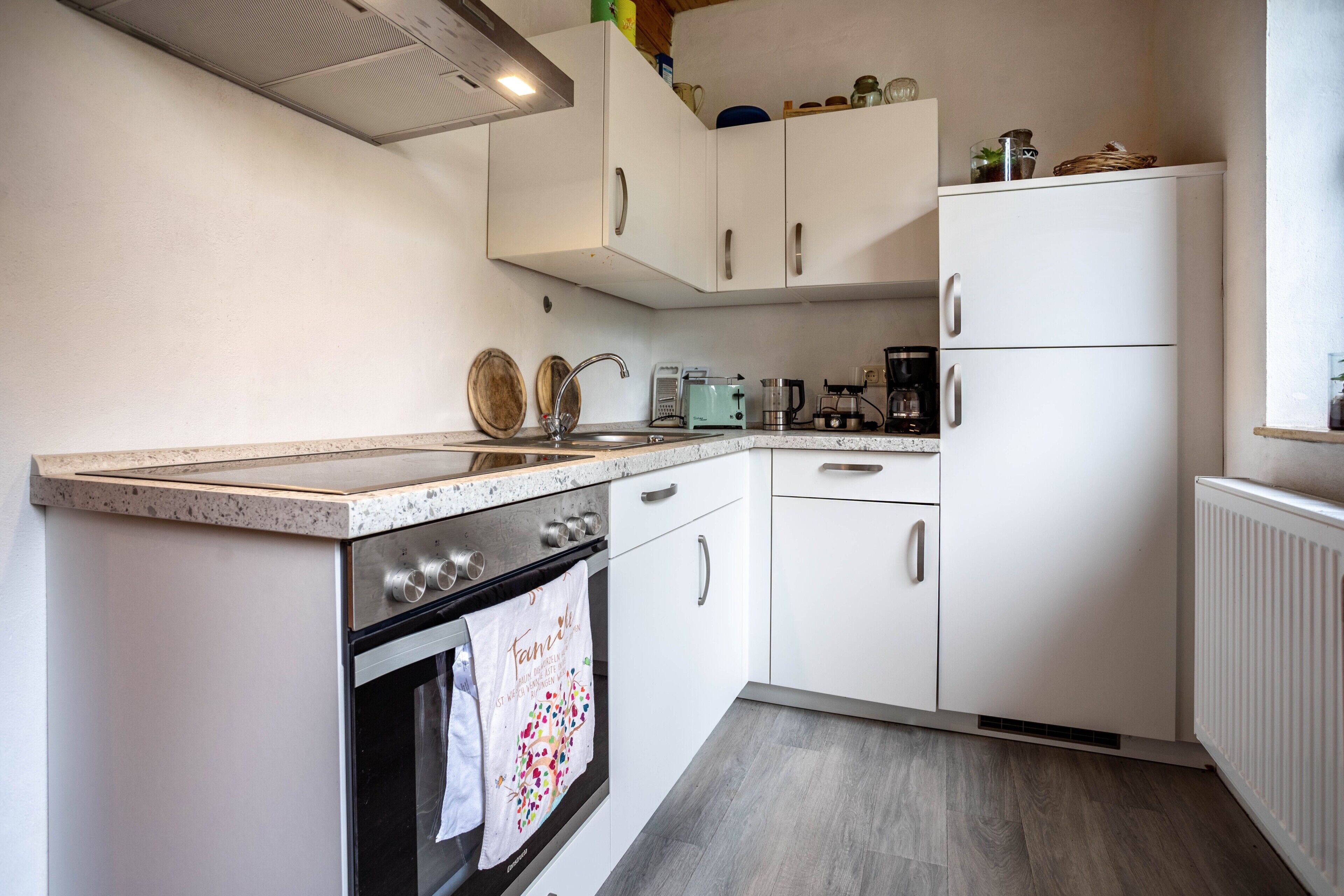 A kitchen with white cabinets, a stove, a sink, and a refrigerator.