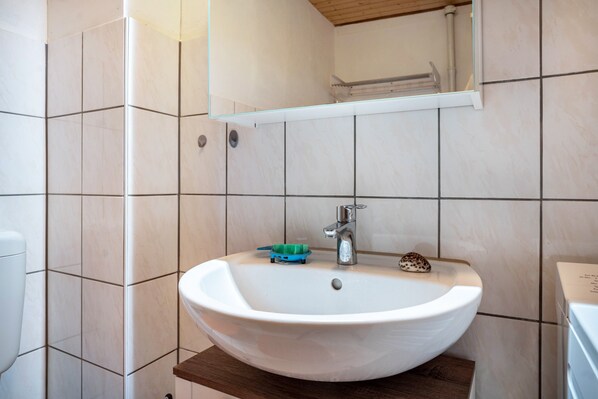 A bathroom with a white sink, a mirror, and a towel rack.