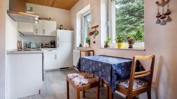 Cocina compacta con comedor, techo de madera y ventanas amplias.