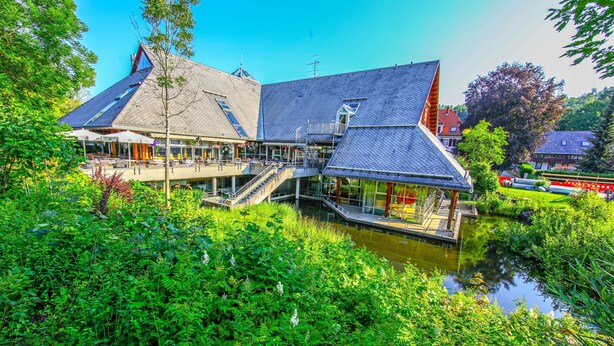 A building with a sloped roof, a water body in front, and a staircase leading to an upper level. - Maisonette Apartment with Mountain View, Balcony, and Wi-Fi (Lenzkirch)