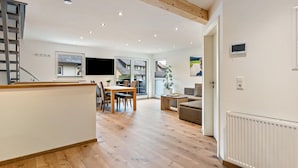 A spacious living area with a wooden floor, a dining table, and a sofa. - Maisonette Apartment with Mountain View, Balcony, and Wi-Fi (Lenzkirch)