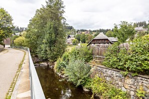 A rural village with a stone wall, wooden fence, and a small stream.