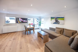 Un salon moderne comprenant un canapé, une table basse et un coin repas avec des chaises.