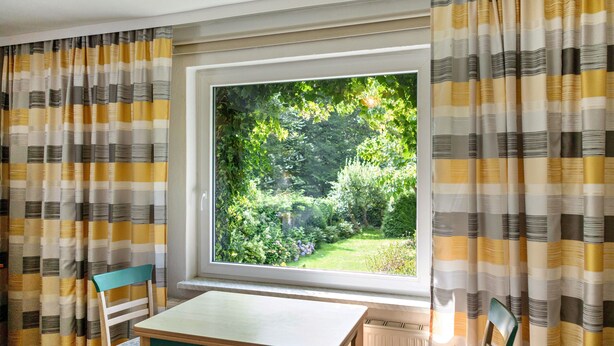 Una habitación con un ventanal grande, una mesa y dos sillas.