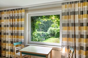 Una habitación con un ventanal grande, una mesa y dos sillas.